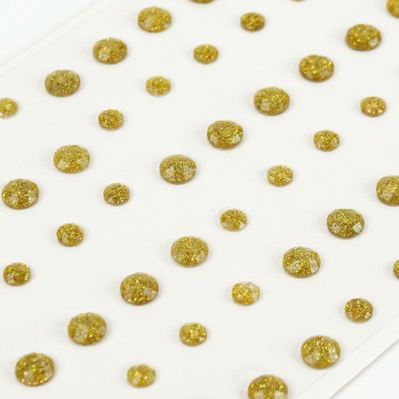 Gold glittery beads scattered on a white surface