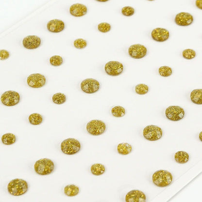 Gold glittery beads scattered on a white surface