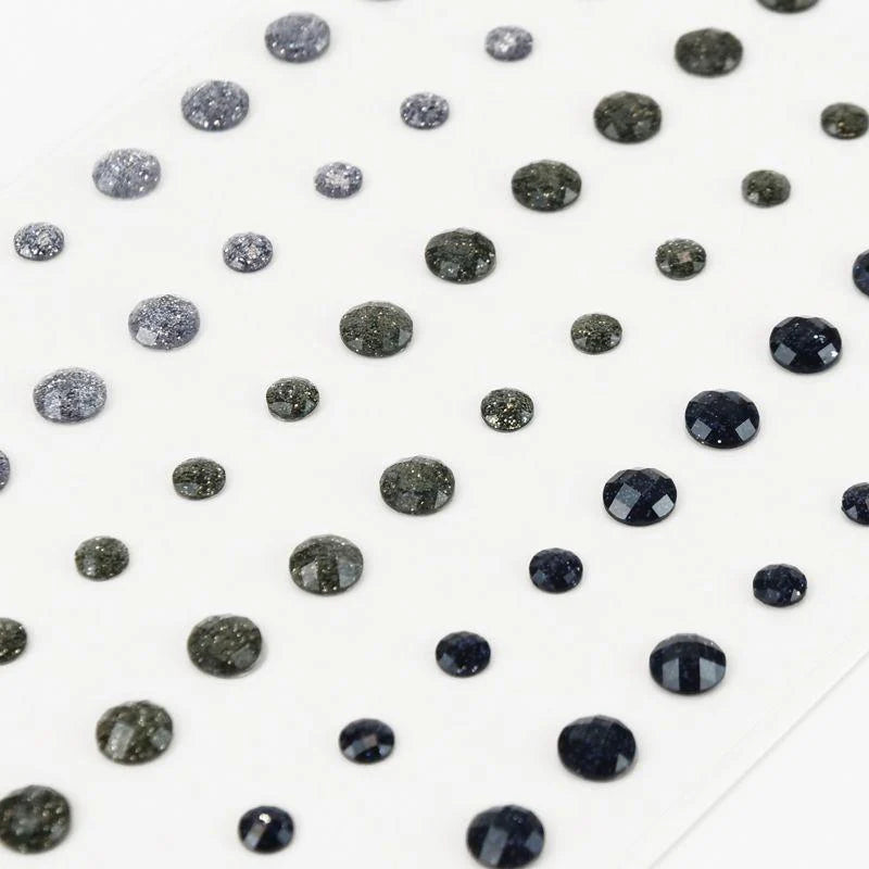 Black rhinestones scattered on a white background