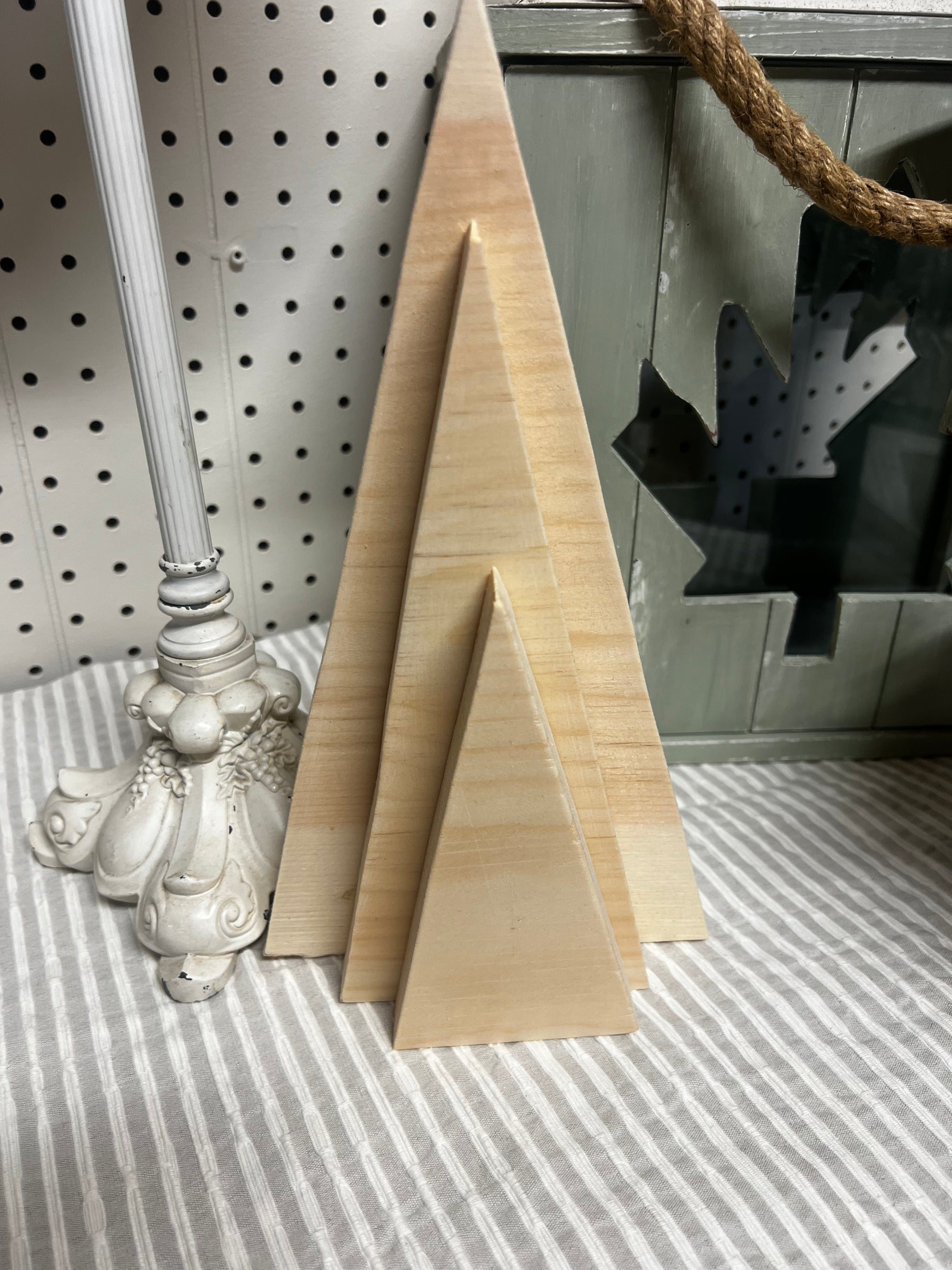 Two wooden triangle blocks on a striped surface with a decorative item in the background.
